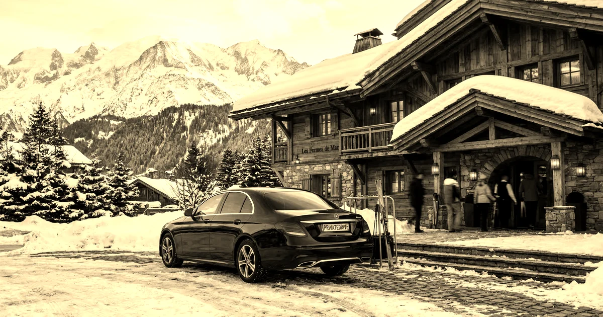 Berline Mercedes Classe E garée devant un chalet de Megève au coucher du soleil sur les Alpes