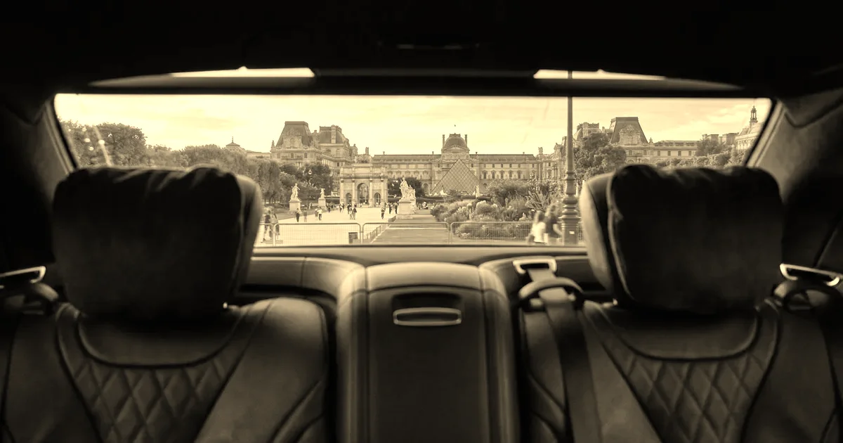 Vue depuis la banquette arrière d’une berline premium sur le jardin des Tuileries et le Louvre à l’heure dorée, traitement sépia presse B2B